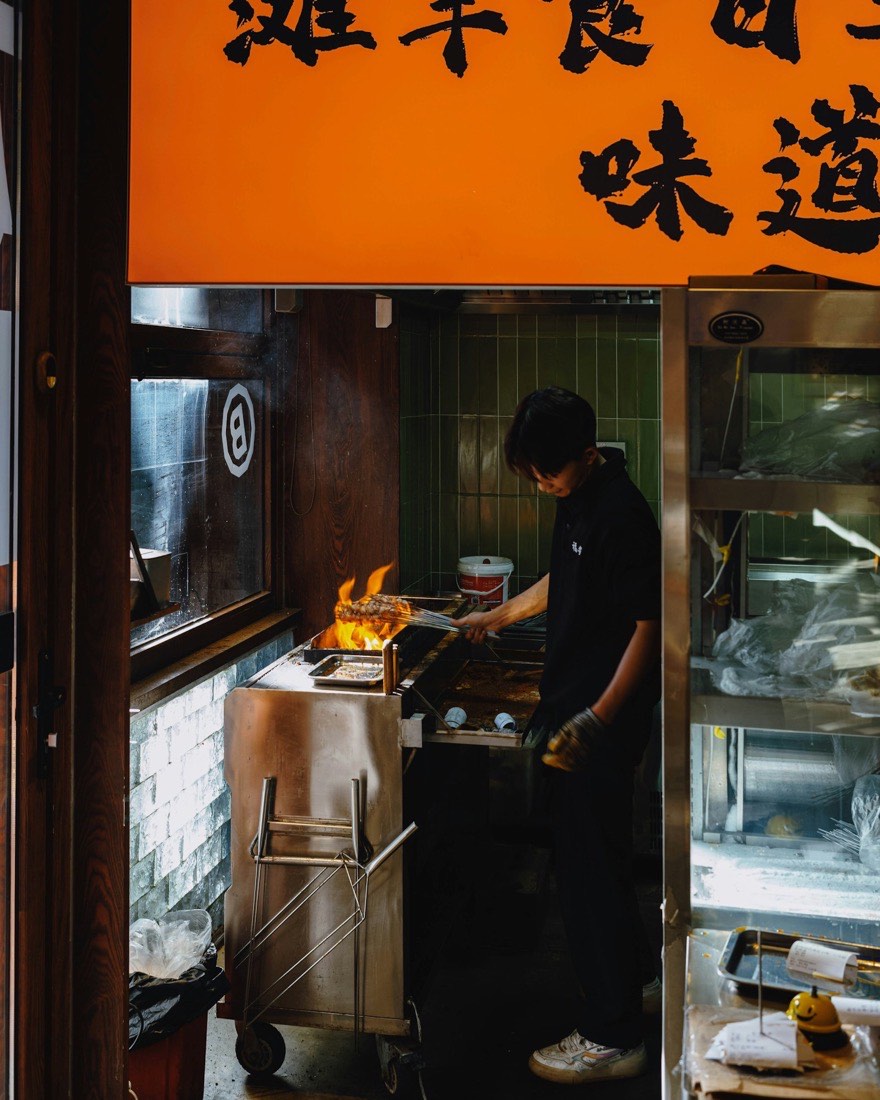 A cook grilling over open flames on the line in a restaurant kitchen
