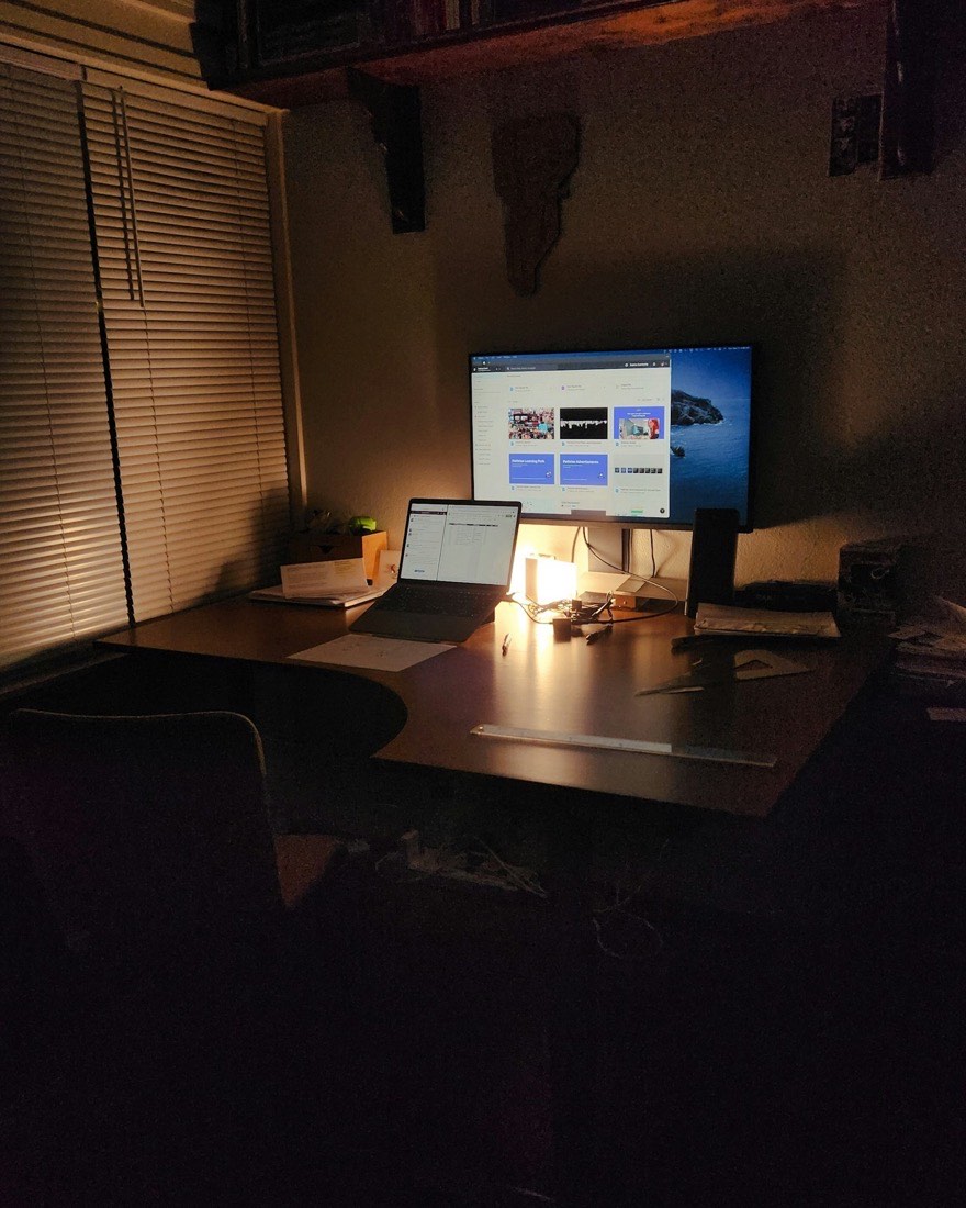 Laptop and monitor glowing in a dark workspace at night
